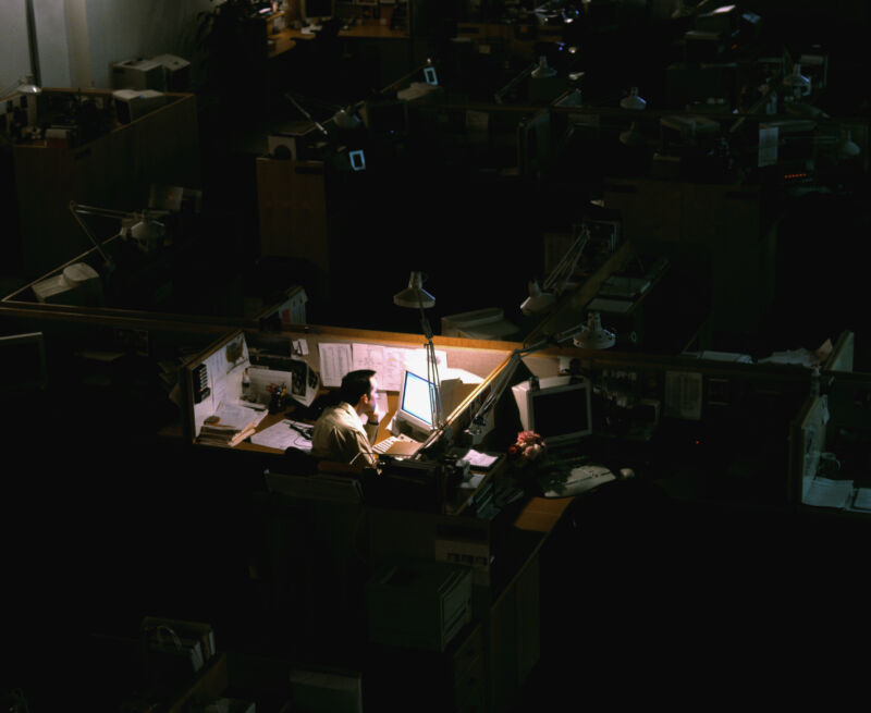 Man working late in dimly lit workspace in dark office space