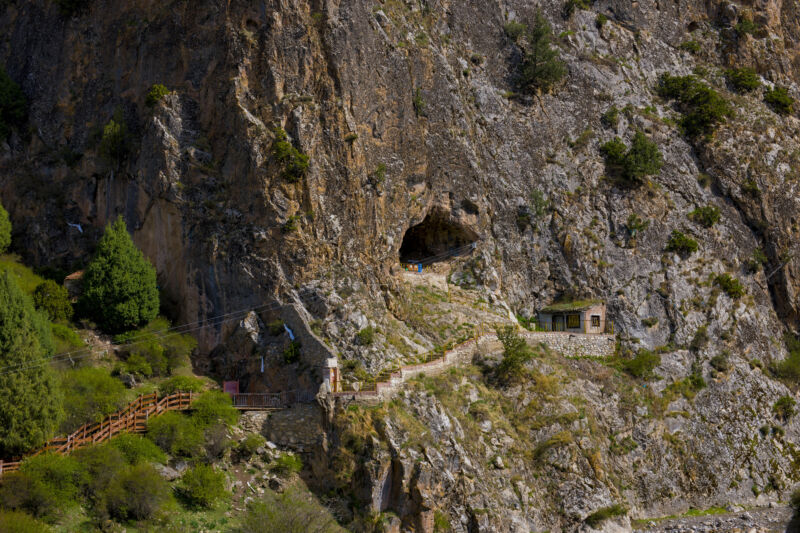 Image of a steep cliff with a narrow path leading to a cave opening.