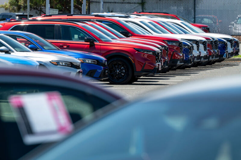 Cars are lined up diagonally at a car dealership.