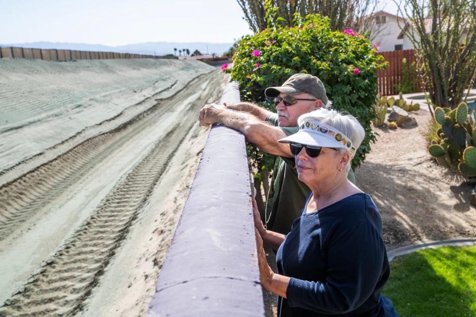 Peter and Jana Koroczynsky look out over the development just north of their Palm Desert backyard. The 11-foot-high sand wall has drawn fierce opposition.