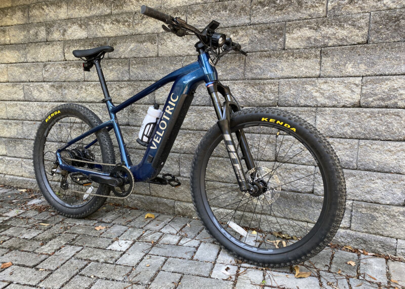 Image of a blue hardtail mountain bike leaning against a gray stone wall.