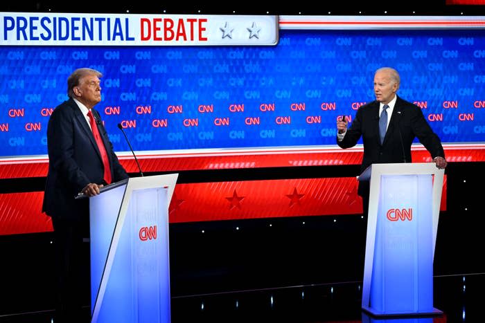 Donald Trump and Joe Biden stand on stage during a CNN-hosted presidential debate, and engage in a discussion. The background shows the text "Presidential debate."