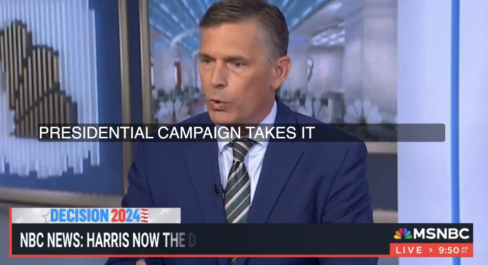 A man in a blue suit and striped tie speaks on an MSNBC news report about a presidential campaign. The screen reads: "NBC News: Harris is now the D..."