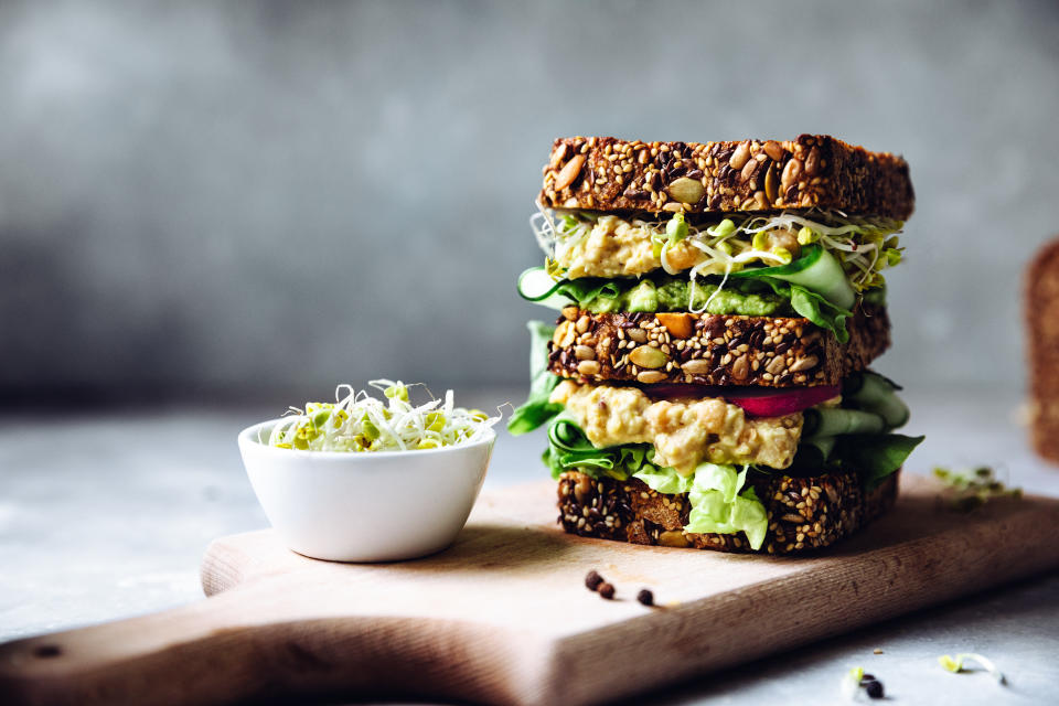 Vegetarian sandwich with sourdough bread, avocado cream, cucumber, radish and remoulade sauce, served on the table.