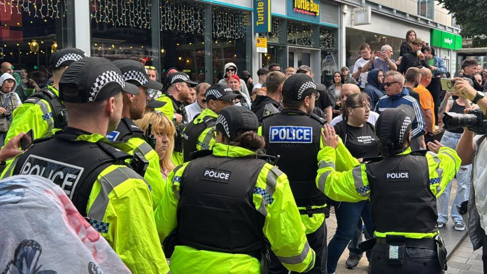 A number of police officers clash with protesters outside shops in Preston