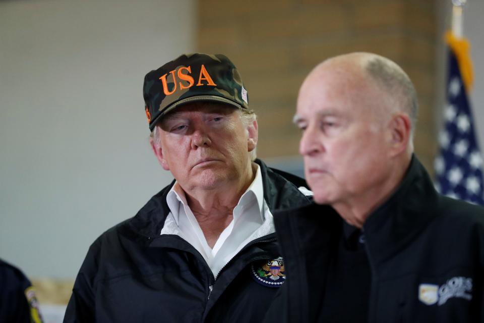 U.S. President Donald Trump looks on as California Governor Jerry Brown speaks during a briefing with state officials after visiting the charred wreckage of a wildfire in Chico, California, on November 17, 2018.