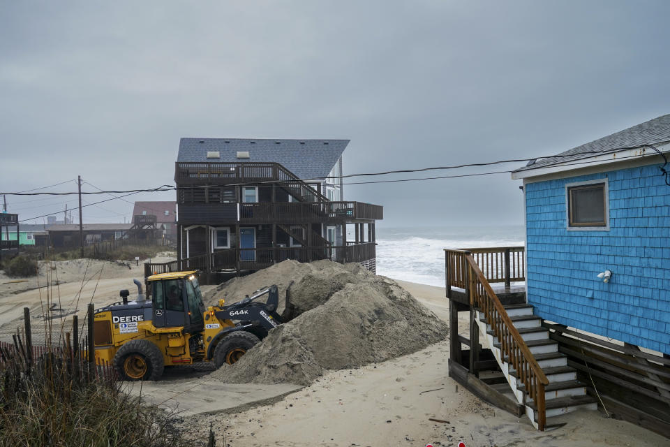 A North Carolina Department of Transportation worker clears ocean-borne sand from Surfside Drive on North Carolina's Outer Banks.