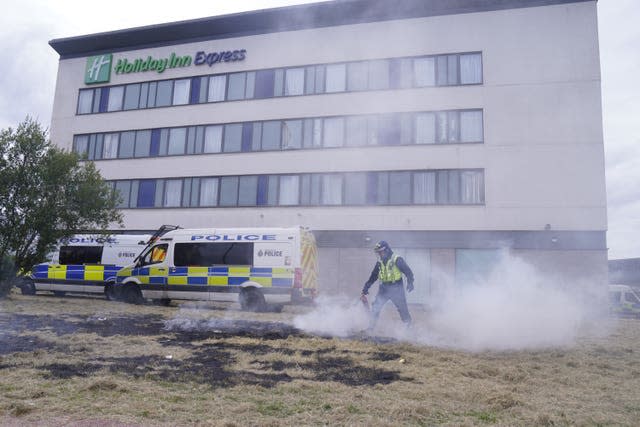 A police officer extinguishes a fire during an anti-immigration protest outside the Holiday Inn Express in Rotherham