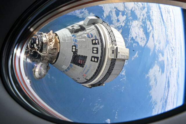 Boeing's Starliner spacecraft docked with the International Space Station, seen through the window of a SpaceX Dragon spacecraft.