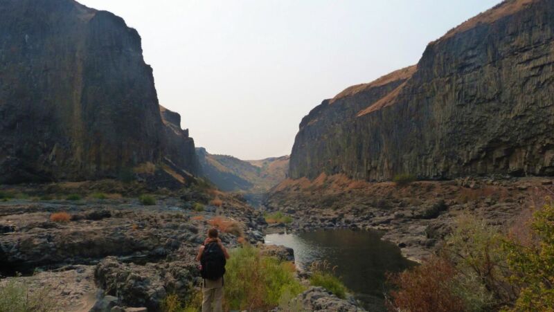 Image of a person in a river-filled gorge between two high rock walls.