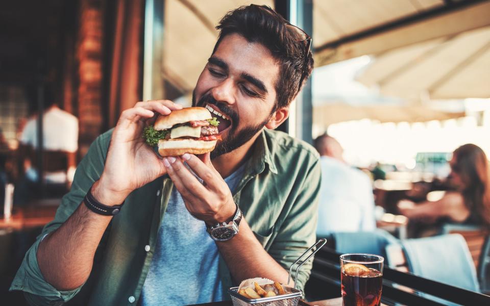 A man enjoys a sandwich in a cafe during his lunch break.