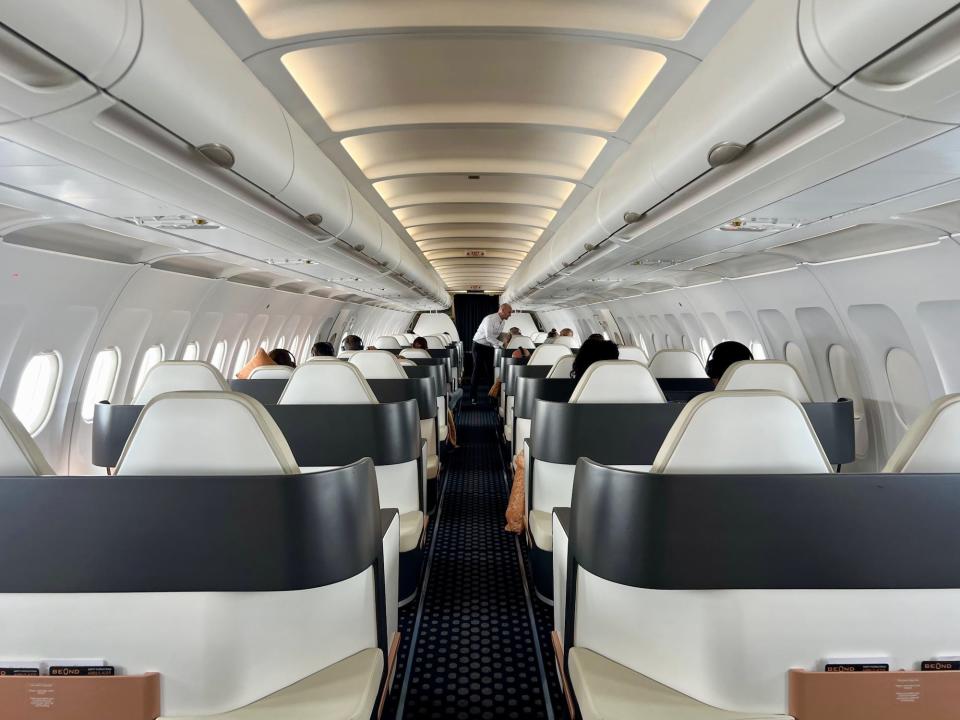 A view of the rear of the Beond cabin, with a flight attendant serving meals.