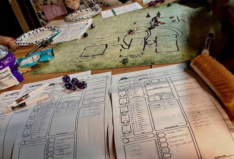 A Dungeons & Dragons game session with a map, miniatures, dice and character sheets