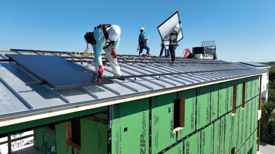 Construction workers are seen securely attaching solar panels to the roofs' raised vertical seams to prevent them from flying off during severe storms in April 2024. - Julian Quinones/CNN/File