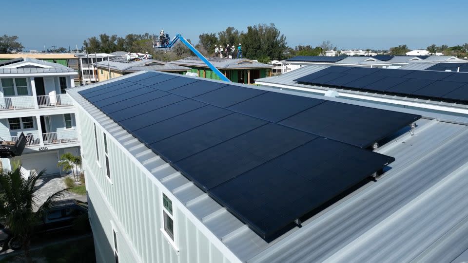 Construction workers are seen securely attaching solar panels to the roofs' raised vertical seams to prevent them from flying off during severe storms in April 2024. - Julian Quinones/CNN/File