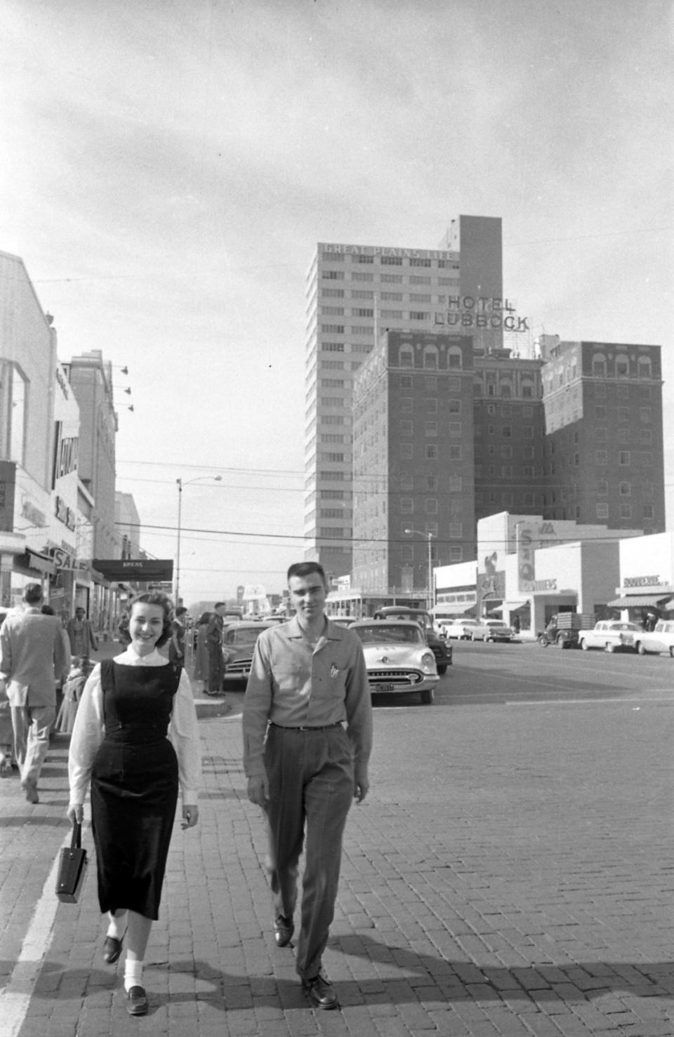 A couple walking through downtown Lubbock with Great Plains Life Building in the background in 1957.