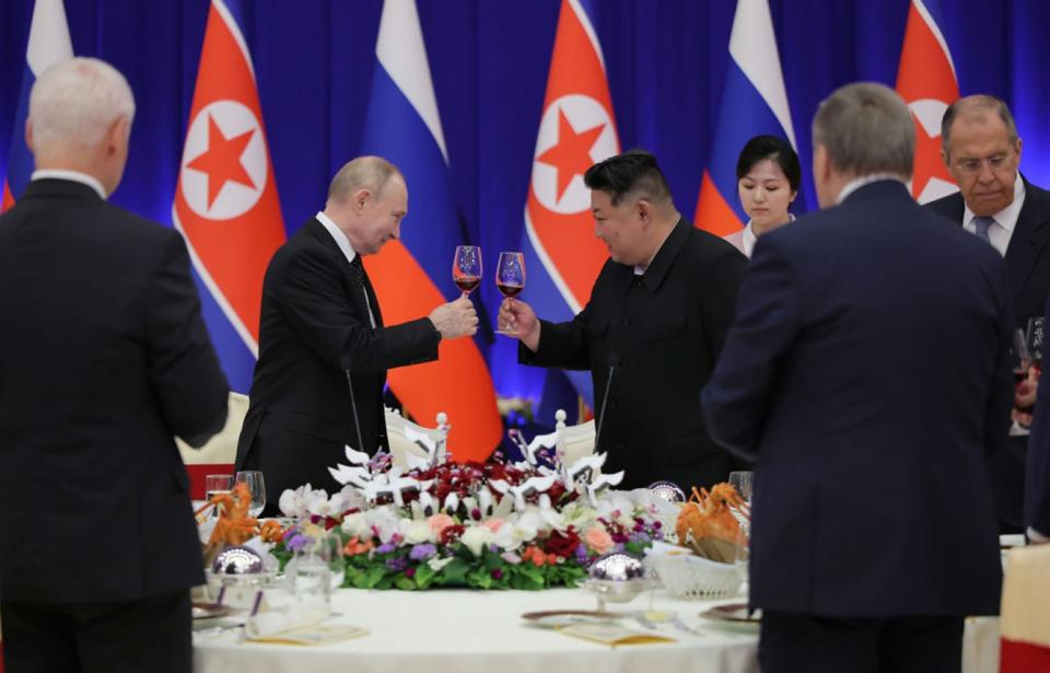 Kim Jong Un and Vladimir Putin toast at a banquet table.