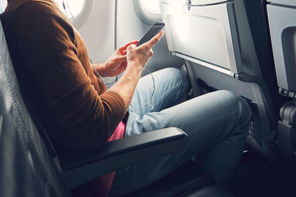 Chalabala/Getty Stock Image Stock image of a passenger on their phone on a plane