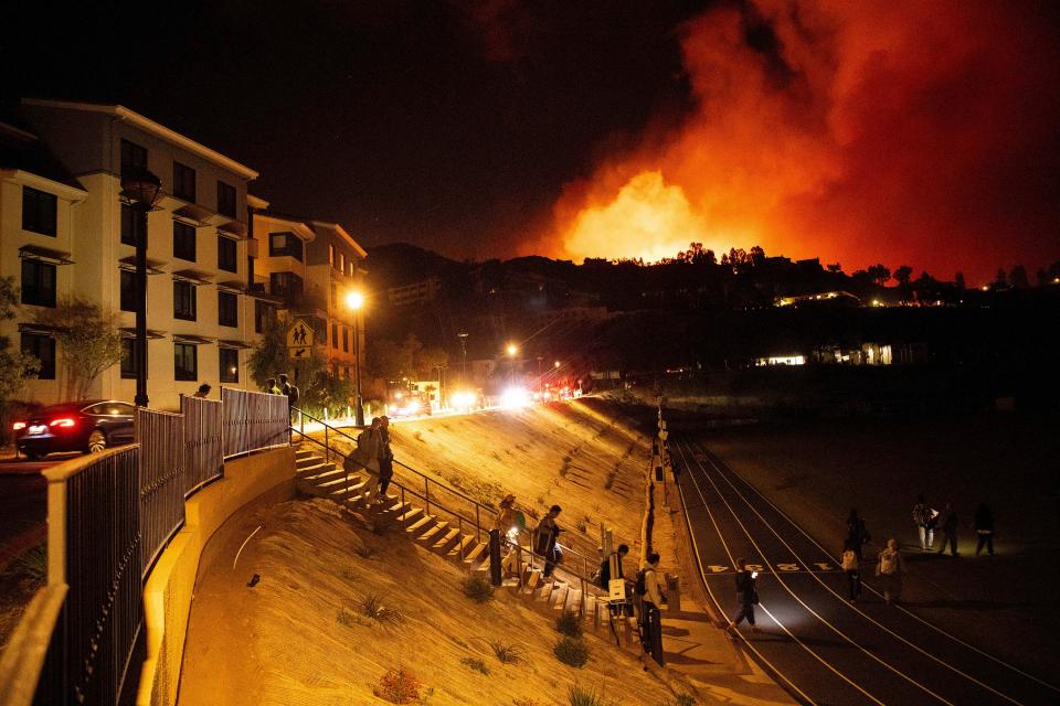 Students evacuate from Pepperdine University on Tuesday as the Franklin Fire burns in Malibu, California. Hazardous weather was expected to continue through Wednesday ((AP Photo/Ethan Swope))