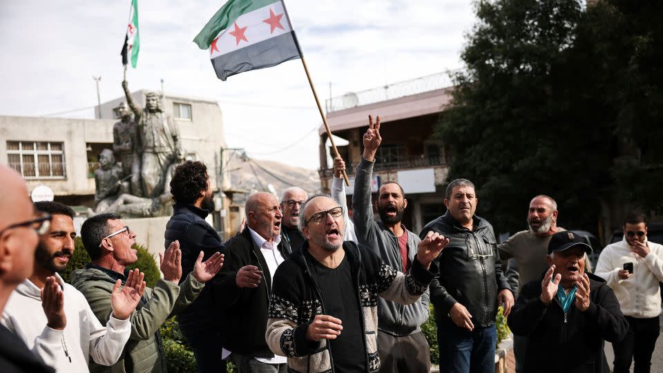 A person holds up a Syrian opposition flag in a Druze village in the Israeli-occupied Golan Heights on December 8, 2024, as men celebrate the fall of the Assad regime. – Stoyan Nenov/Reuters