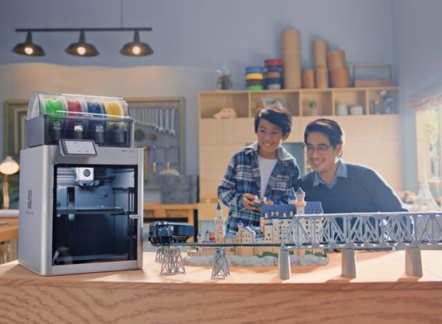 Father and son smile as they look at what looks like a train bridge, with a photoshopped Bambu Labs X1 tucked in nearby.