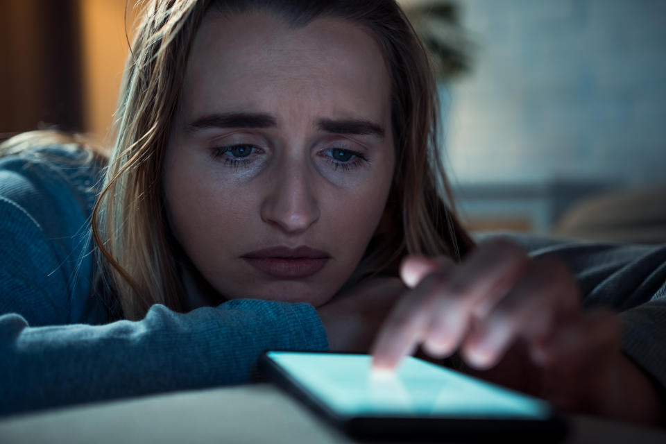 Trieste woman with a smartphone in the living room. Depression concept.