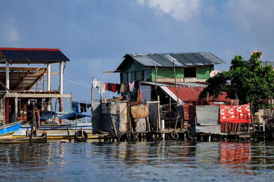 Houses built of wood and wave costs metal on platforms above water, with washing drying, on Gardi Sugdub, June 2024