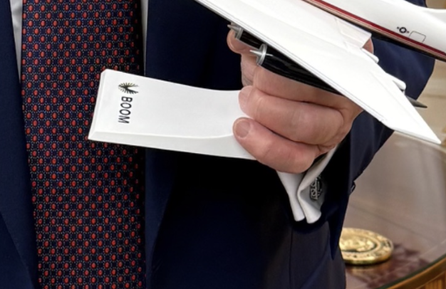 Person in formal clothing holds a model plane with "Tree" Written on the wing