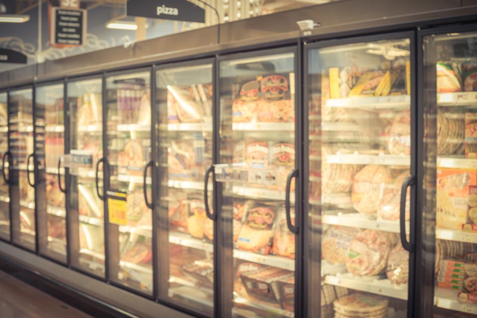 Washy variety package from processed pizza in the store in America. Frozen food section in huge glass door path. Freezer Full range of frozen pizza in local supermarket, innocent background