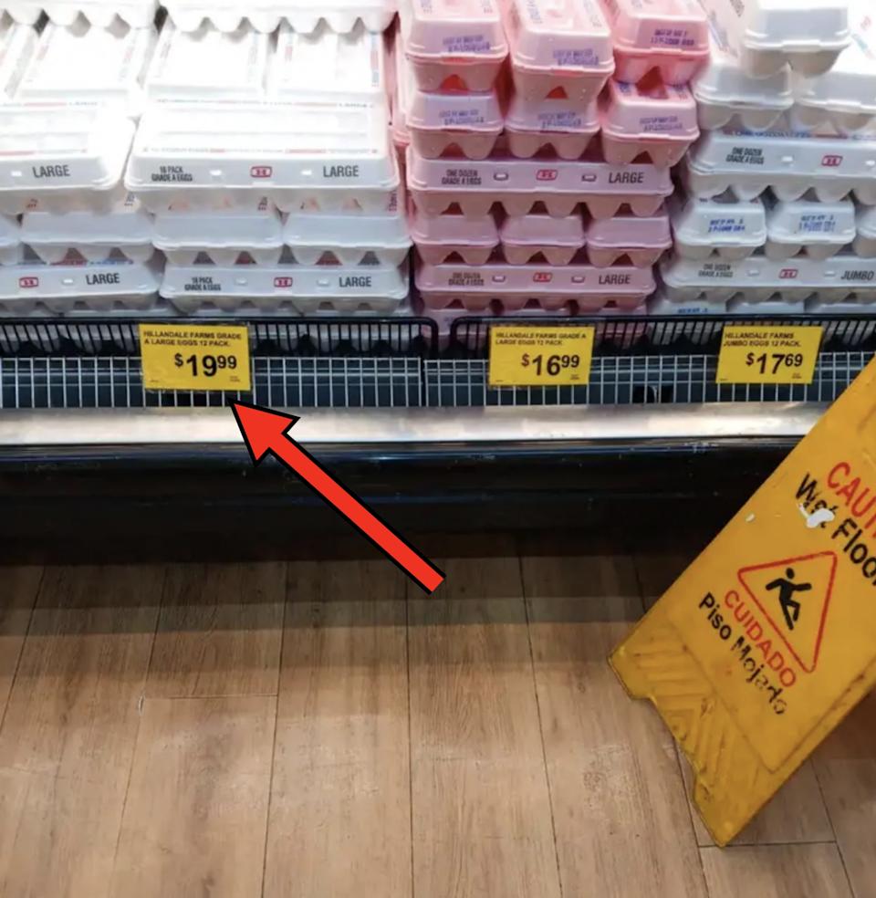 Egg boxes are stacked with three different prices visible: $ 19.99, $ 16.99 and $ 17.69. A caution of the floor is on the right