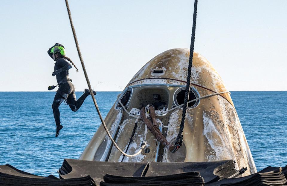 A SpaceX Support Team member is seen in the air while working to lift the SpaceX Dragon Capsule on a recovery vehicle after landing off the coast of Florida.