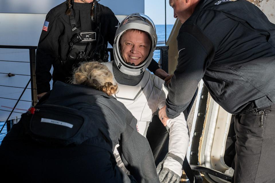 Roscosmos Cosmonaut Aleksandr Gorbunov is helped from a SpaceX Dragon spacecraft.