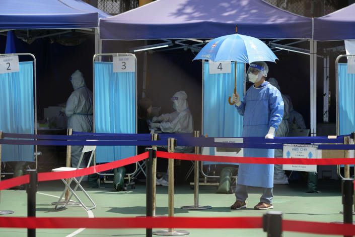 Workers wearing protective clothing in a temporary testing center.