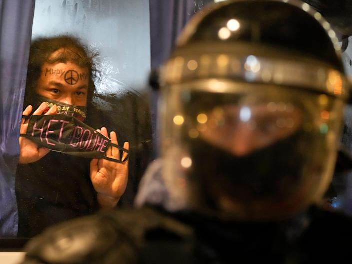 A detained protester displays a 'No War!' sign  from a police van in St. Petersburg, Russia.