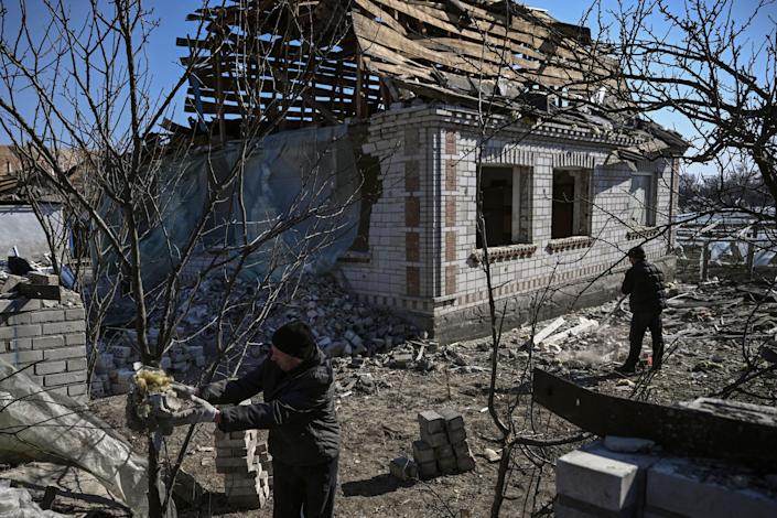 People working around the site of a destroyed house.