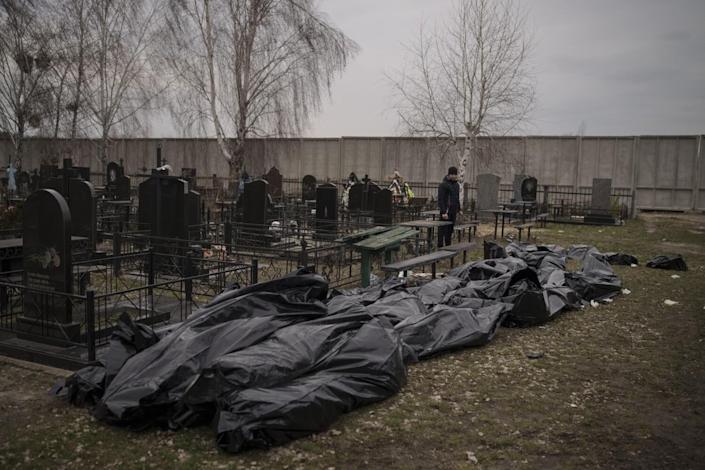 Bodies in black bags lie near tombstones