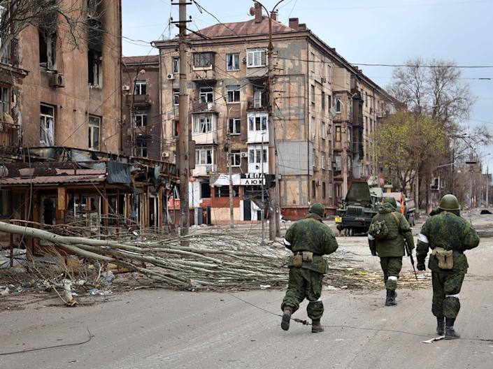 Soldiers of the militia of the Donetsk People's Republic walk past damaged apartment buildings near the Illich Iron & Steel Works Metallurgical Plant, the second largest metallurgical enterprise in Ukraine, in an area controlled by Russian-backed separatist forces in Mariupol, Ukraine, Saturday, April 16, 2022. Mariupol, a strategic port on the Sea of ​​Azov, has been besieged by Russian troops and troops from self-declared separatist areas in eastern Ukraine for more than six weeks.  (AP Photo/Alexei Alexandrov)