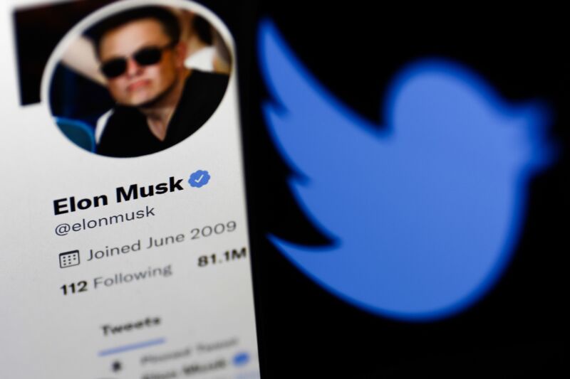 Elon Musk's Twitter profile displayed on a computer screen next to a Twitter logo displayed on a phone screen