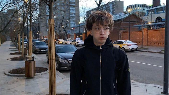 Daniil Orain on a street at dusk.  He wears big glasses and looks sideways.