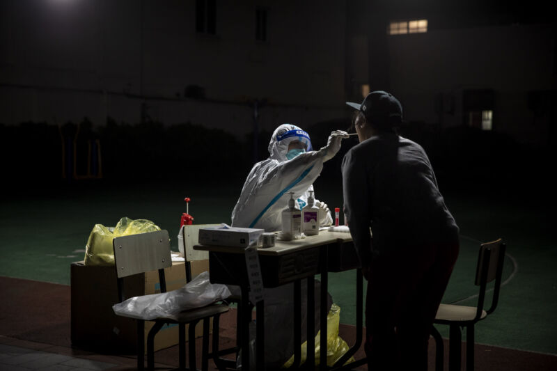 A Personal Protective Equipment (PPE) worker collects a swab from a resident for a COVID-19 test on Saturday, April 9, 2022, in a closed-off neighborhood in Shanghai, China. 