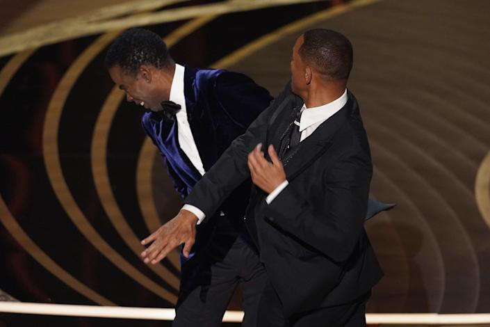 Will Smith, right, hits host Chris Rock onstage during the Oscars Best Documentary Award ceremony at the Dolby Theater in Los Angeles on Sunday, March 27, 2022.