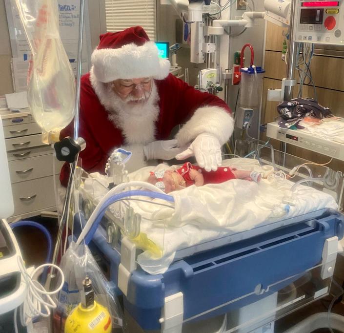 Wearing an oxygen mask, Santa visits little Nola Soteropoulos in AdventHealth for Children's neonatal intensive care unit in Orlando.