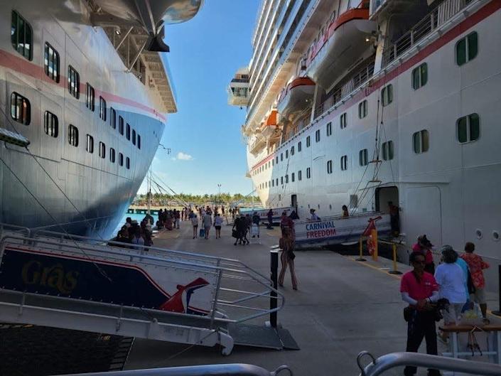 Passengers leave Carnival Freedom, right, on Thursday morning to spend the day in Grand Turk after a funnel fire on the ship was brought under control.  To the left is Carnival's Mardi Gras.  Both ships are stationed in Port Canaveral.