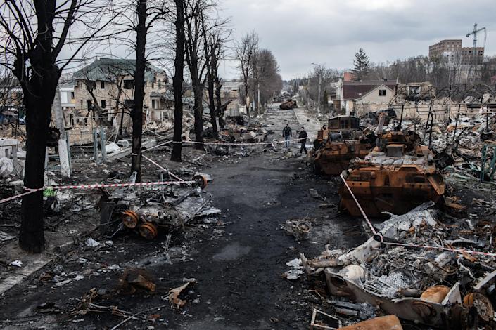 A city street is seen with burnt tanks strewn about.