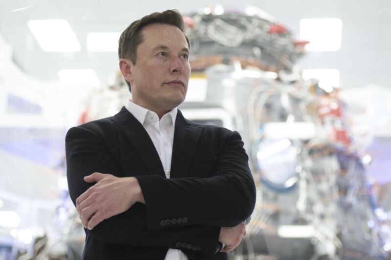 SpaceX CEO Elon Musk stands with his arms folded.