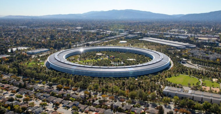 A huge ring-shaped building on a green campus.