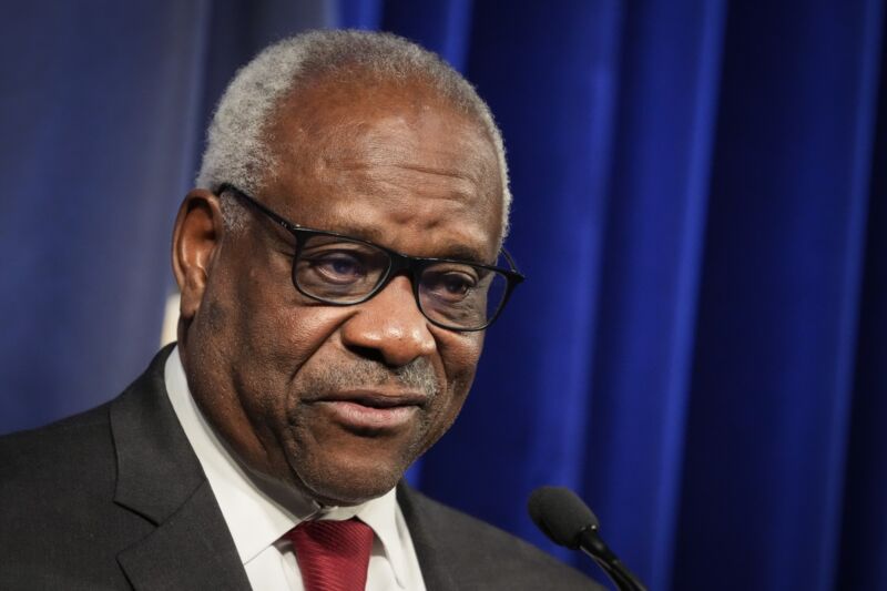 Supreme Court Justice Clarence Thomas speaks into a microphone at an event.