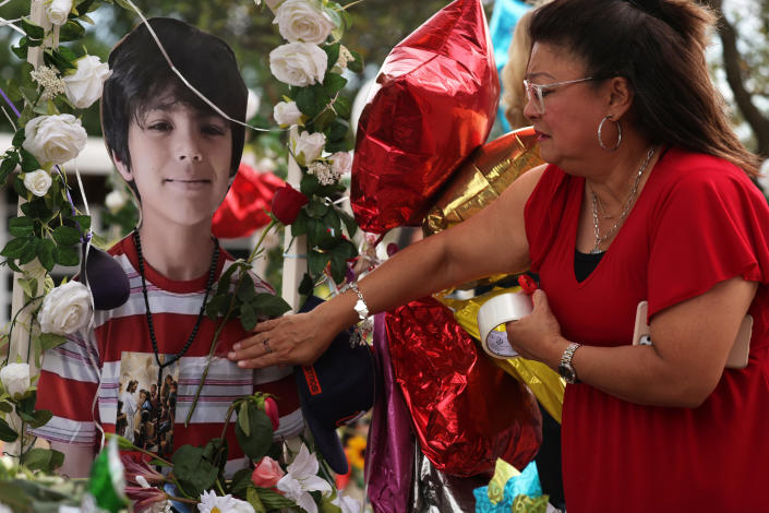 UVALDE, TEXAS - JUNE 01: Yvette Reyes of San Antonio puts a rose in the photo of a shooting at a memorial outside Robb Elementary School, June 1, 2022 in Uvalde, Texas.  Nineteen students and two teachers were killed on May 24 after an 18-year-old gunman opened fire at the school.  There are vigils and funerals for the 21 victims throughout the week.  (Photo by Alex Wong/Getty Images)