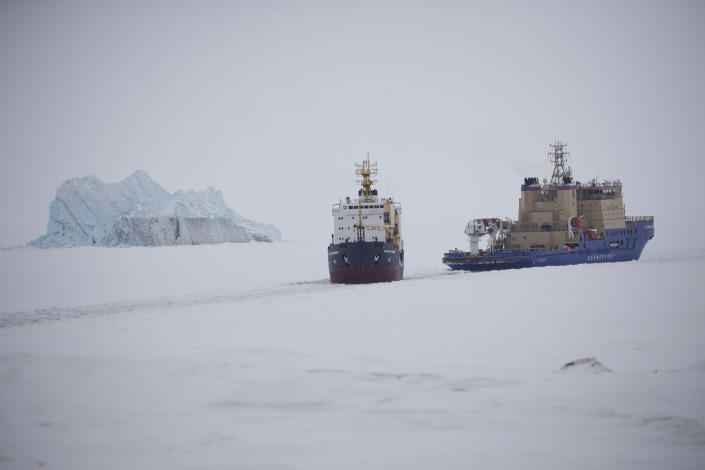 An icebreaker clears a path for a cargo ship near Nagurskoye, Russia