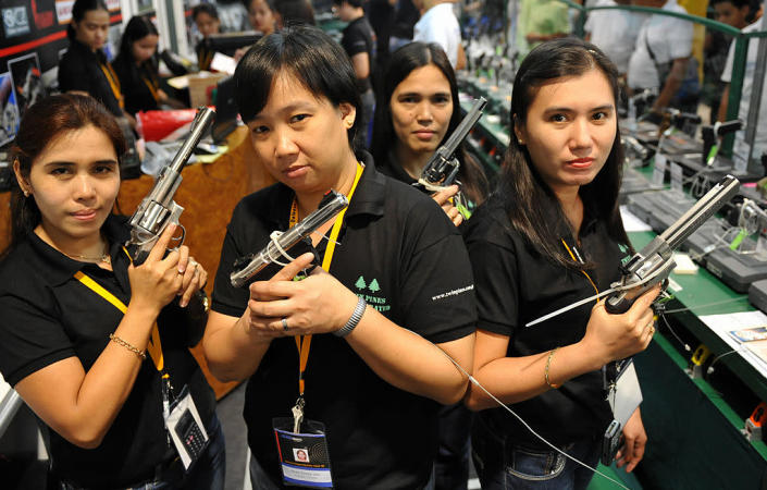 Shop assistants posing with different handgu